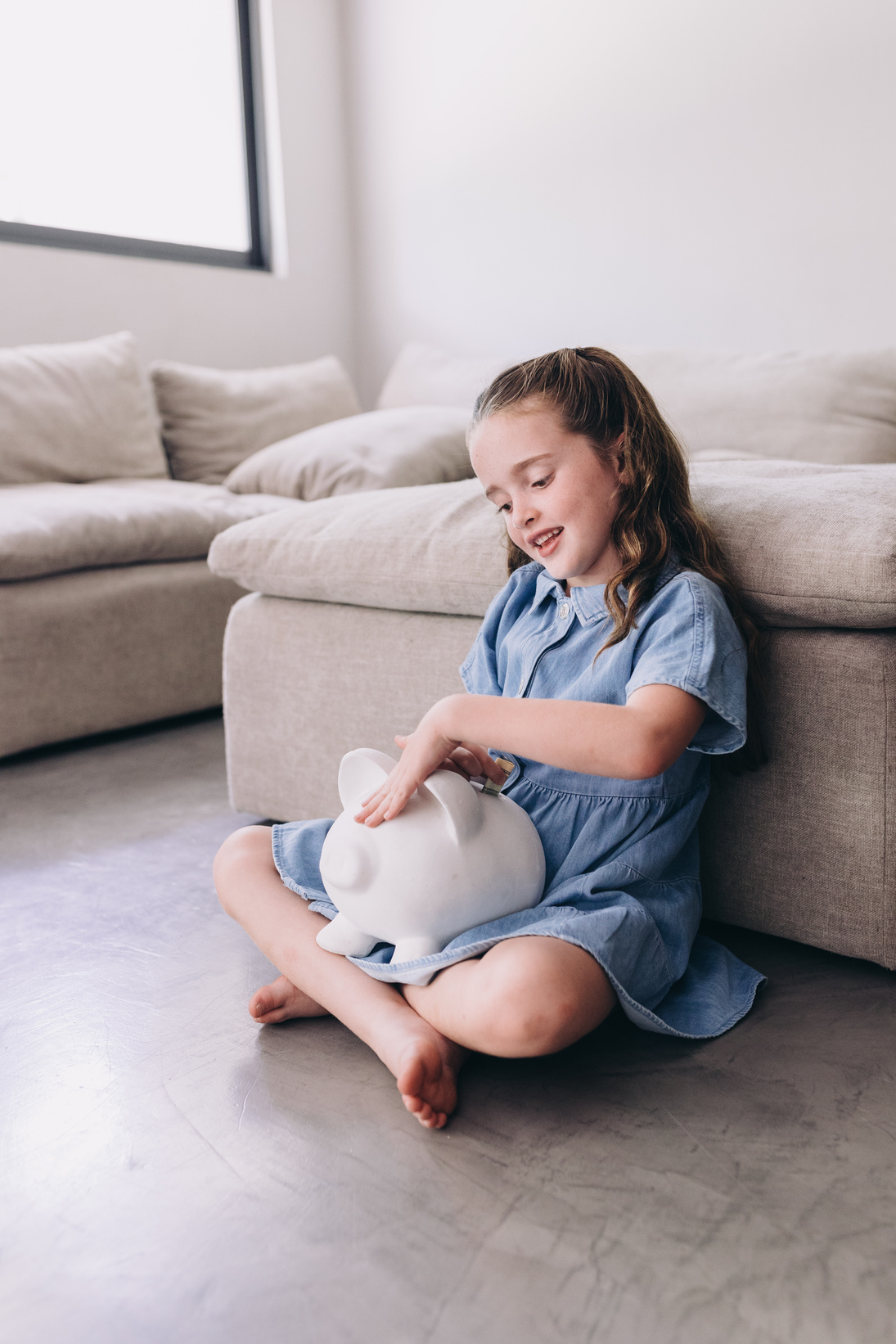 Child Putting Money in Piggy Bank