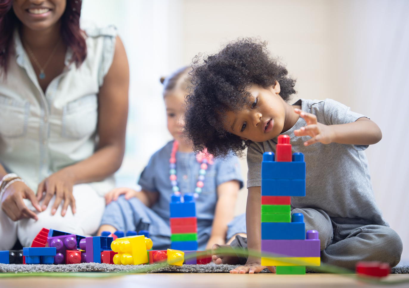 Daycare teacher builds blocks with toddlers