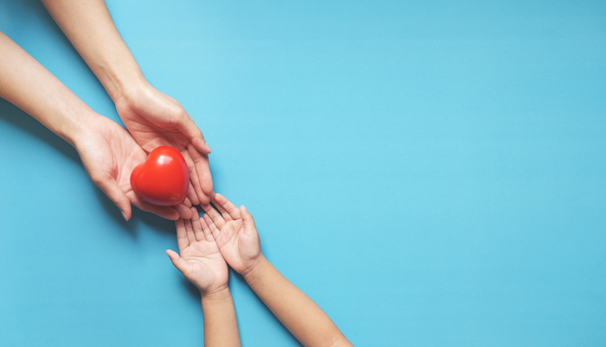 Red Heart on Child and Mother Hands with Copy Space